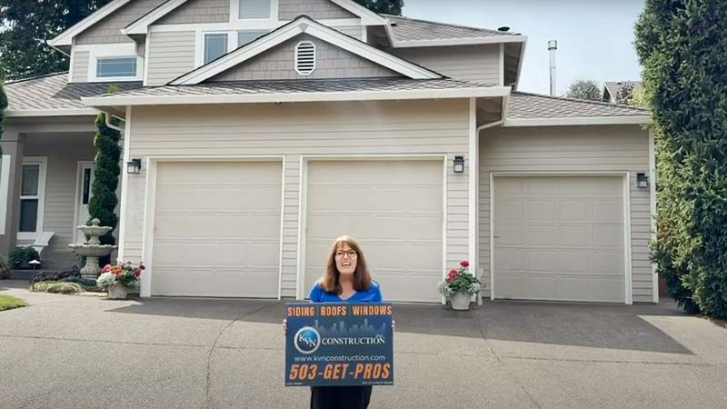 Woman holding a KVN construction sign in front of a house.